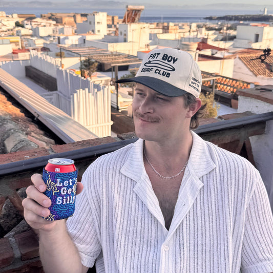 Man sitting holding a drink with a neoprene "Let's Get Silly" beer Koozie.