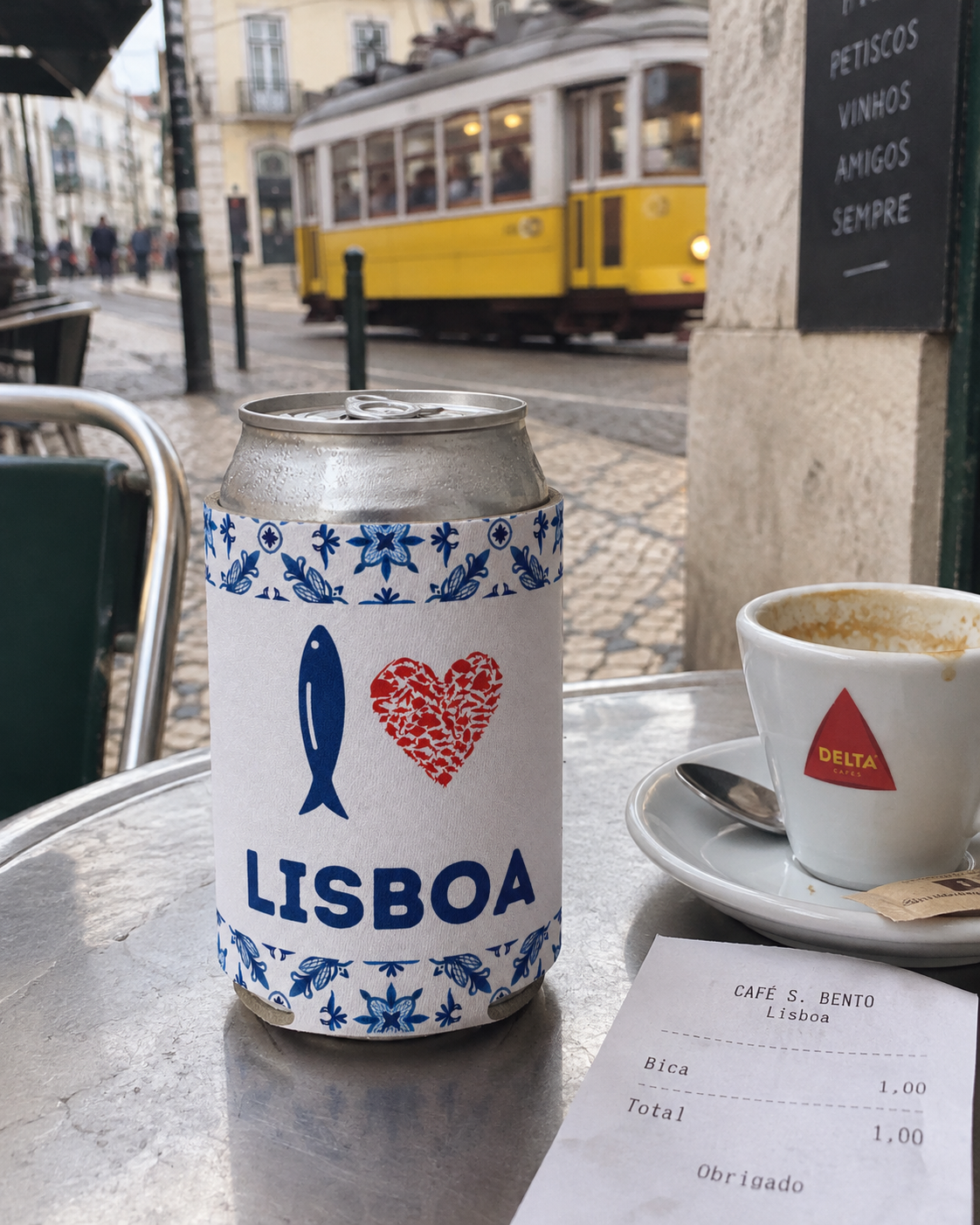 I Love Lisboa White koozy at a Lisbon esplanada cafe with a yellow tram passing
