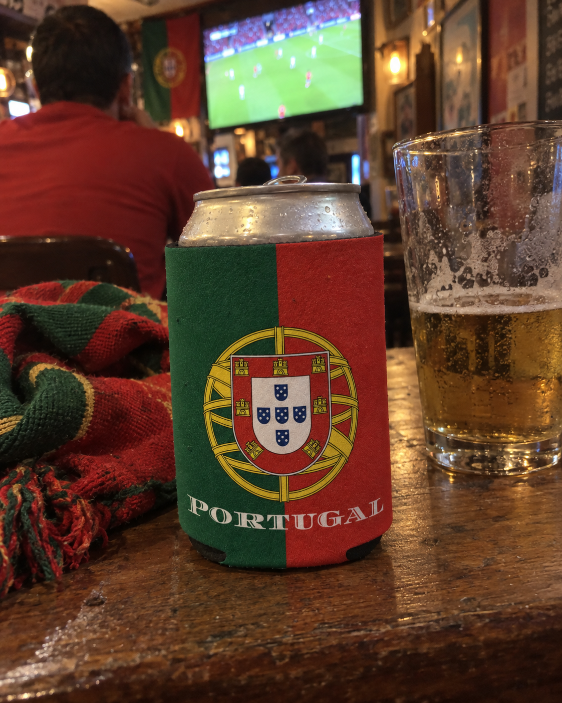 Portugal Flag koozy on a wooden table in a sports bar during a football match